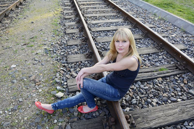 Young woman sitting on railroad track