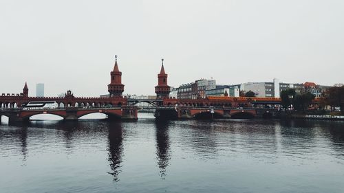 Bridge over river in city against clear sky