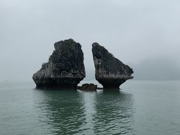 Rock formation in sea against sky