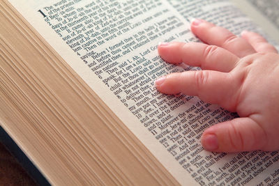 Close-up of hand holding book with text