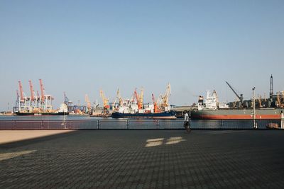 Man walking by boats moored at commercial dock