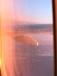 Close-up of airplane wing over sea against sky