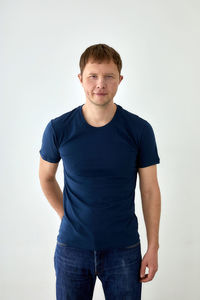 Portrait of young man standing against white background