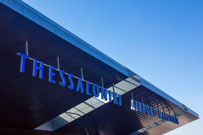 Low angle view of text on building against clear blue sky