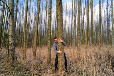 Man hugging tree trunk at forest