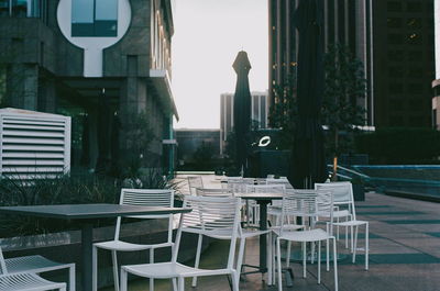Empty chairs and tables in cafe in city