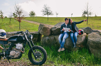 Full length portrait of friends sitting on field