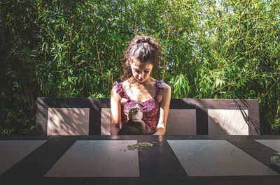 Young woman sitting on table against plants