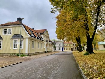 Street amidst trees and buildings against sky