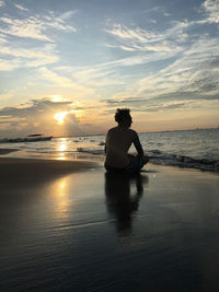 Rear view of man on beach against sky during sunset