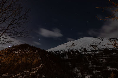 Low angle view of snowcapped mountains against sky at night