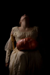 Girl with pumpkin against black background