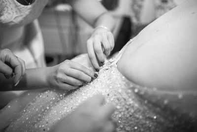 Cropped hands of bridesmaid adjusting wedding dress of bride