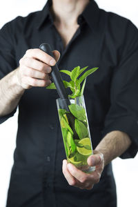 Cropped image of hand holding leaf over white background