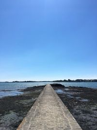 View of empty road against clear blue sky