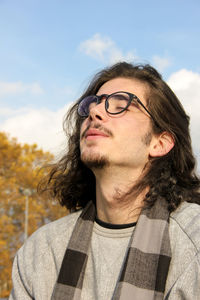 Close-up of young man wearing eyeglasses against sky