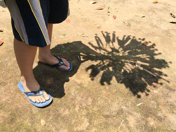 Low section of man holding object with shadow on ground