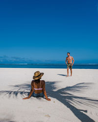 Rear view of woman standing at beach against clear sky