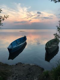 Boat moored on sea against sky during sunset