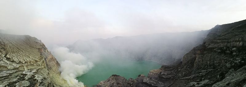 Panoramic view of volcanic mountains by sea against sky