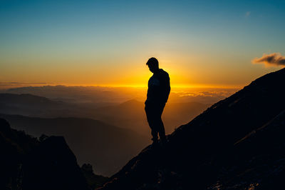 Silhouette man standing on mountain against sky during sunset