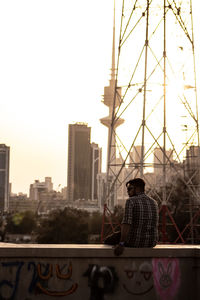 Rear view of man standing by buildings against clear sky