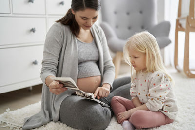 Pregnant woman teaching daughter at home