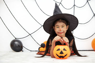 Portrait of smiling boy with arms outstretched against trees during halloween