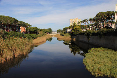 Scenic view of lake by buildings against sky