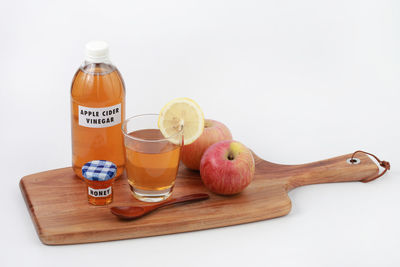 Close-up of drink with fruits on table against white background