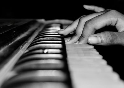 Close-up of hand playing piano in dark