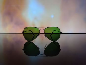 Close-up of leaf on glass table against sky