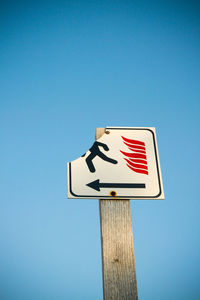 Low angle view of road sign against clear blue sky