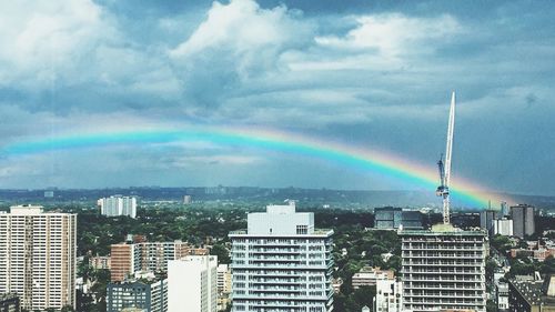 Rainbow over cityscape against sky