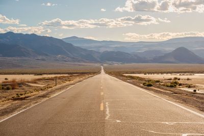 Road leading towards mountains against sky