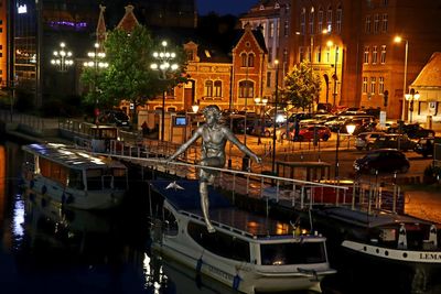 Sailboats moored on canal in city at night