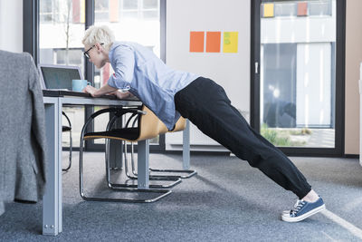 Businesswoman in office doing push ups on desk