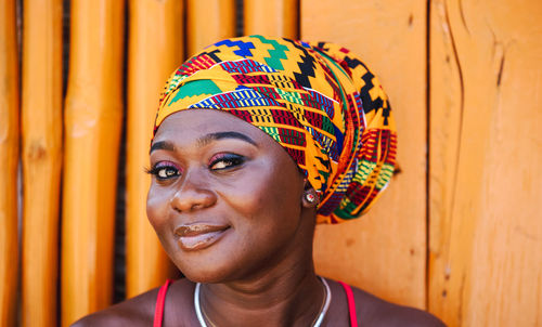 African woman with a hopeful happy smile standing against a bamboo wall