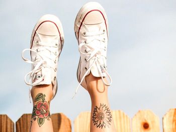 Low section of woman wearing shoes on beach