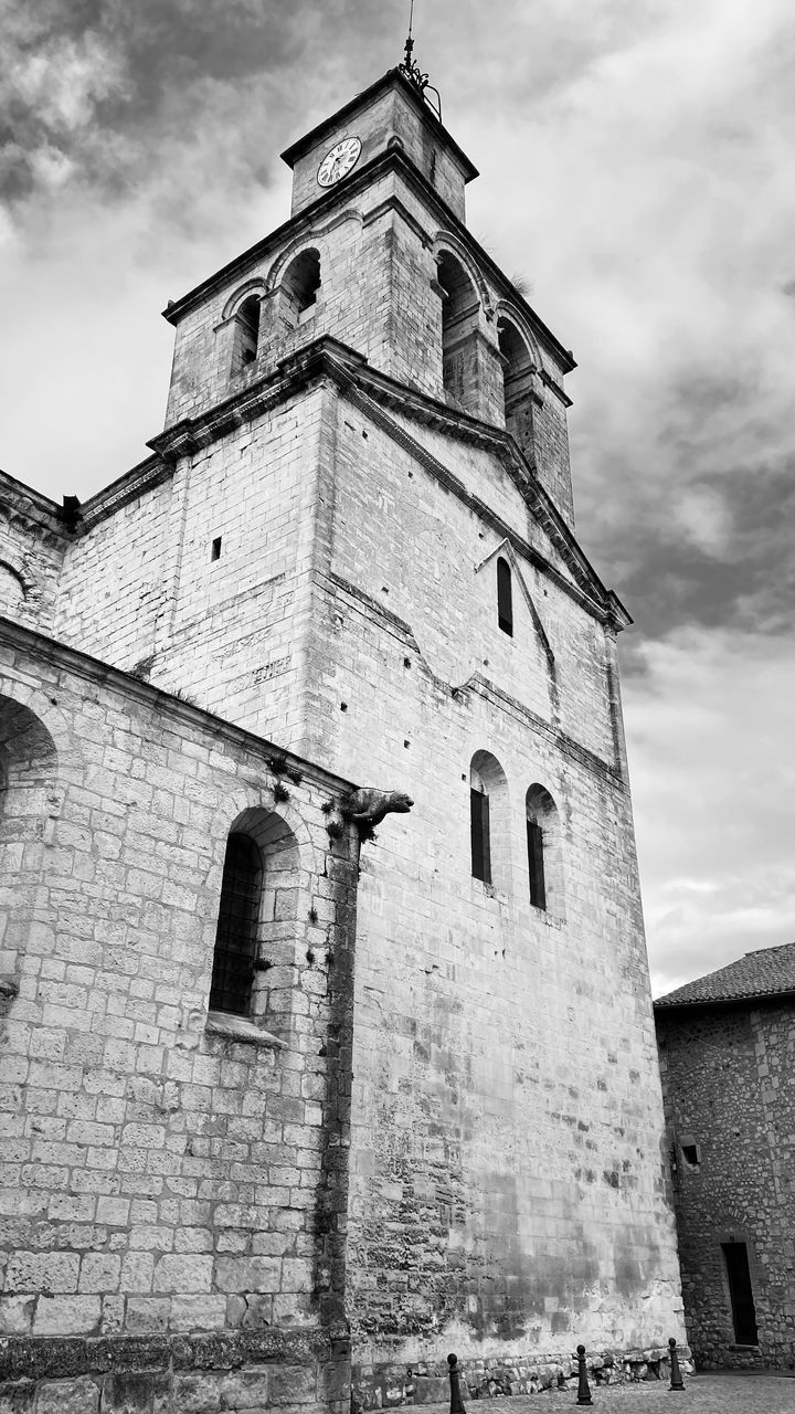 LOW ANGLE VIEW OF OLD TOWER AMIDST BUILDINGS AGAINST SKY