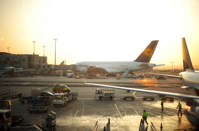 Airplane on airport runway against clear sky during sunset