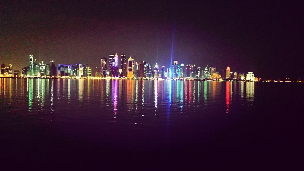 illuminated, night, water, building exterior, architecture, built structure, reflection, city, waterfront, sea, sky, cityscape, river, skyscraper, urban skyline, outdoors, mid distance, no people, light - natural phenomenon, tall - high