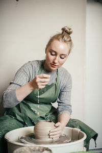 Young woman learning pottery on a potter's wheel