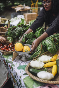 High angle view of female vendor keeping yellow courgettes on table at farmer's market