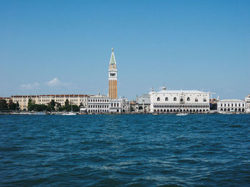 Buildings in city against clear blue sky