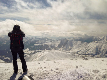 Rear view of man standing on snowcapped mountain. man on winter mountains background.