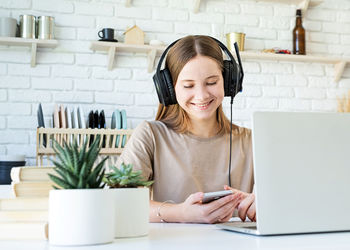 Portrait of smiling young woman using phone on table