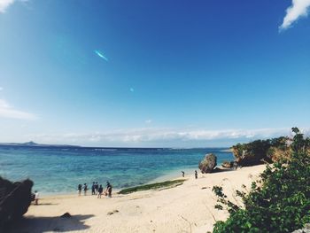 People on beach against blue sky