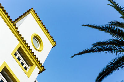 Low angle view of yellow building against clear blue sky