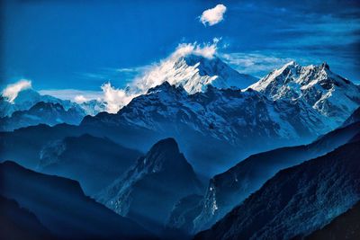 Scenic view of snowcapped mountains against blue sky